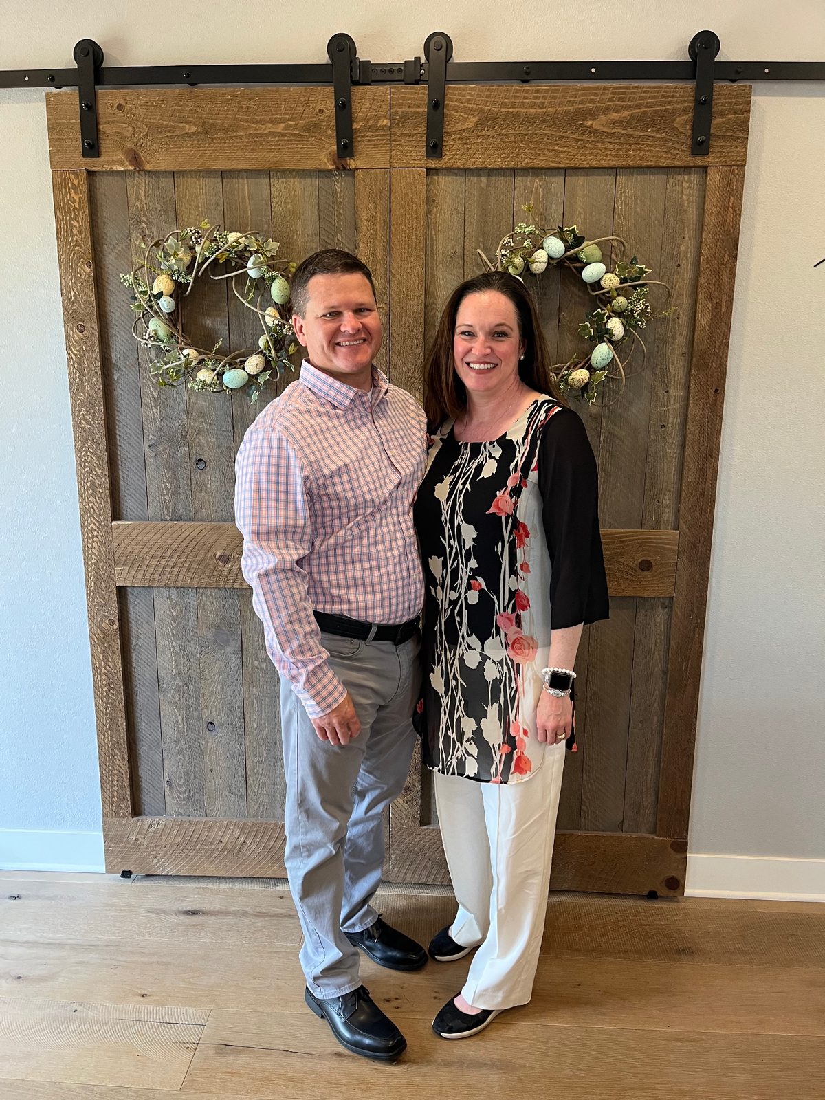 Julie and Jay in front of rustic barn doors with spring wreaths