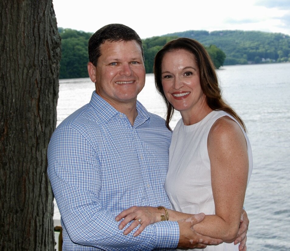 Julie and Jay by a lake with rolling green hills